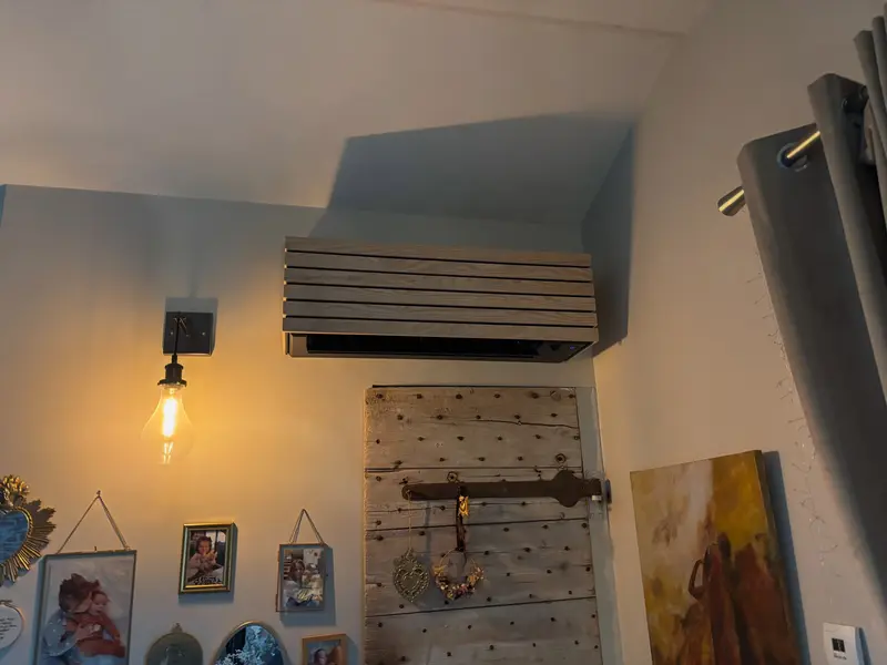 Climatisation habillée d'un cache en lames de bois